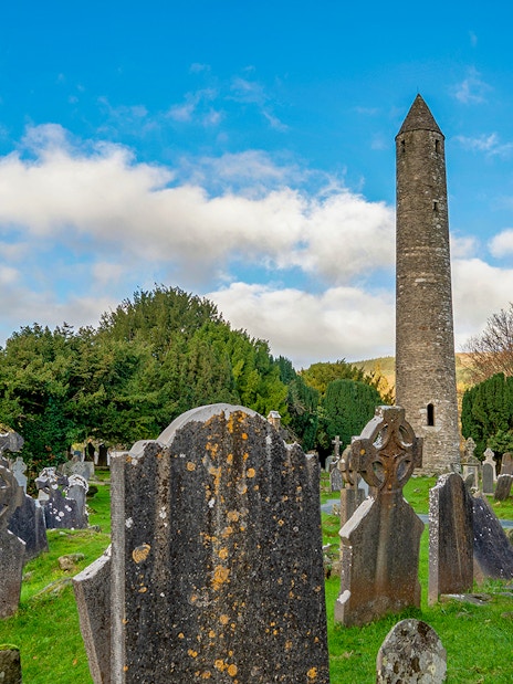 Glendalough Monastic site with round tower and ancient gravestones in a lush valley.