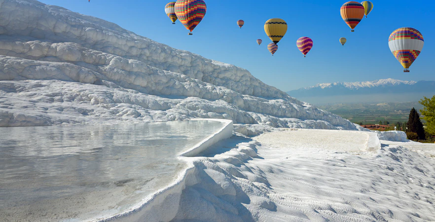 Hot air balloons over Pamukkale's travertine pools and limestone terraces, Turkey.