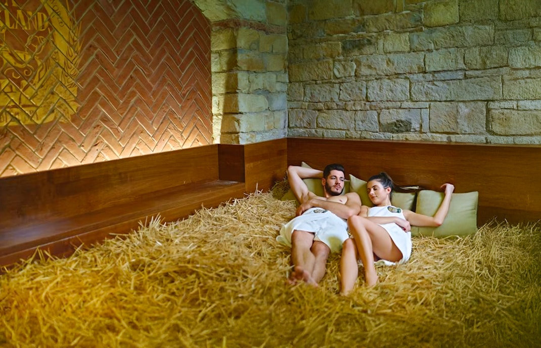 Couple resting in wheat straw bed at Prague Spa Beerland