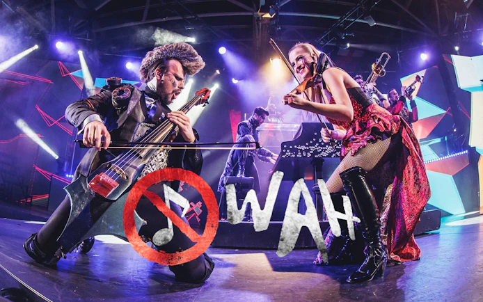 Musicians performing energetically on stage with WAH logo in foreground.