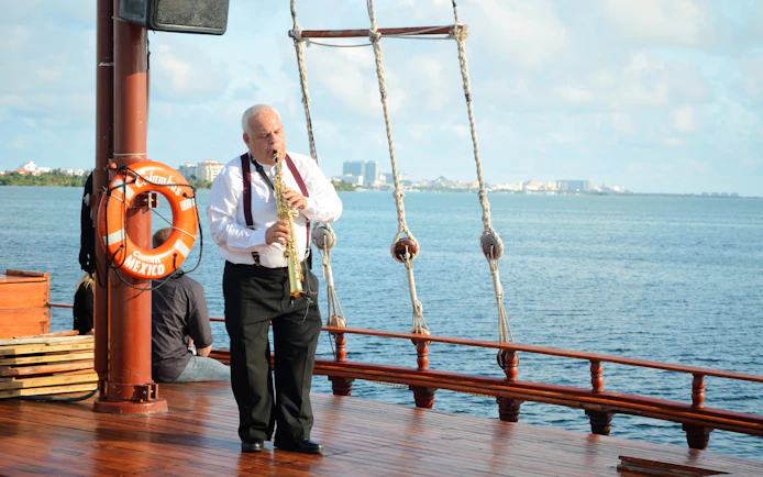 Saxophonist performing on deck during Columbus sunset cruise in Cancun.