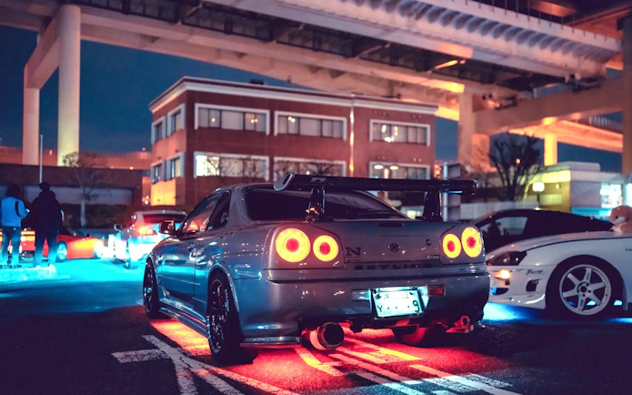 Skyline 34 at Daikoku PA car meeting, inspired by Fast and Furious, under highway lights.