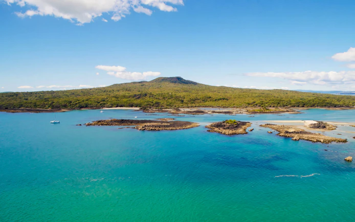 Rangitoto Island with volcanic landscape and blue waters, viewed from Auckland ferry.