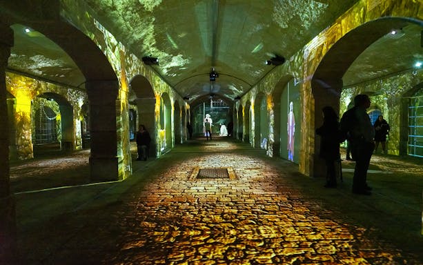 Porto Legends immersive experience with projections in a historic stone archway.