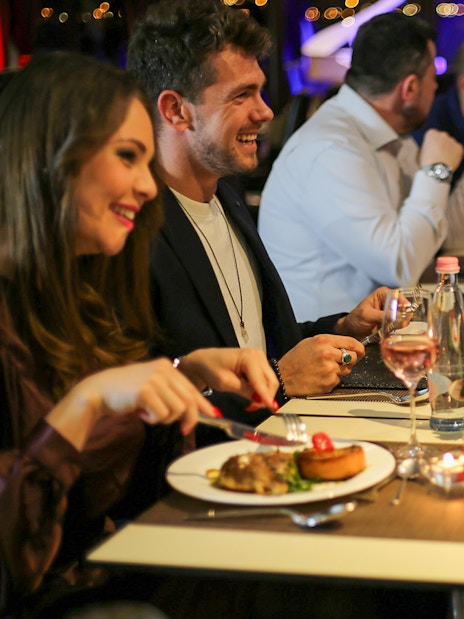 Guests dining on a Budapest dinner cruise with a piano battle show.