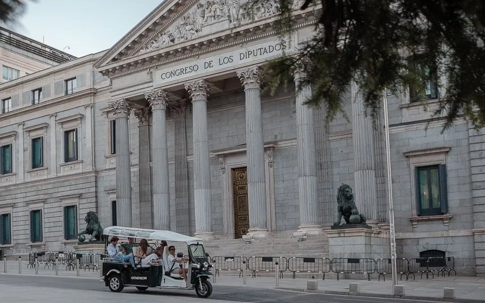 Tourists on an electric tuk-tuk in front of Congreso de los Diputados, Madrid, Spain.