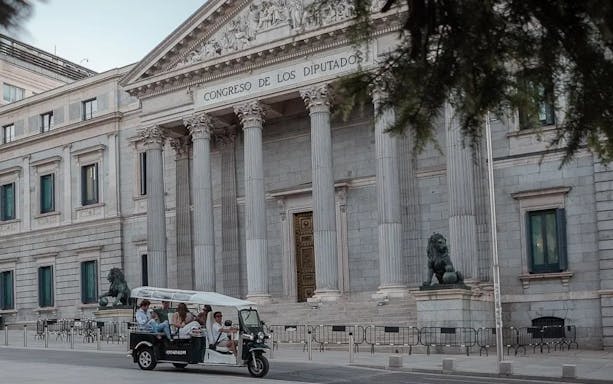 Tourists on an electric tuk-tuk in front of Congreso de los Diputados, Madrid, Spain.