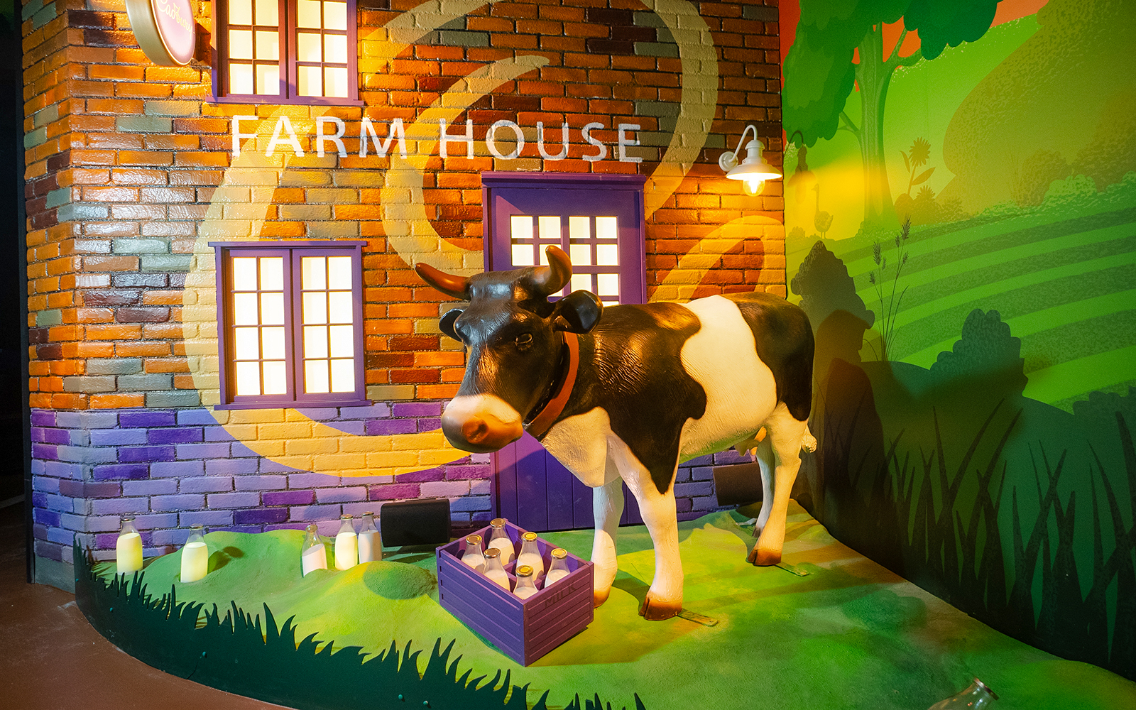 Cow statue at Cadbury World farm exhibit with milk bottles.