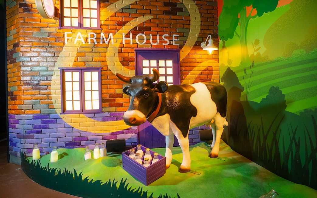 Cow statue at Cadbury World farm exhibit with milk bottles.