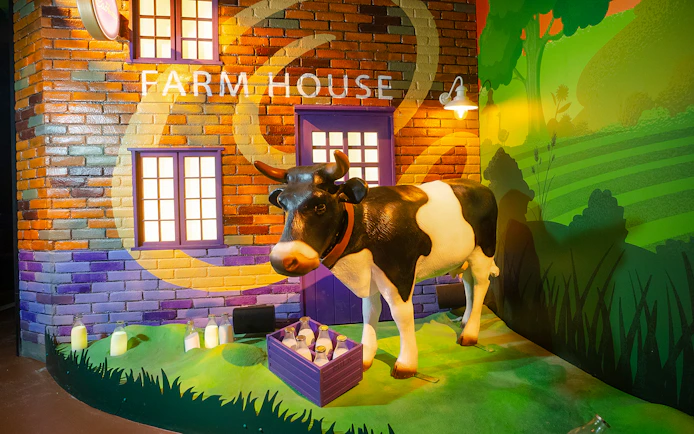 Cow statue at Cadbury World farm exhibit with milk bottles.