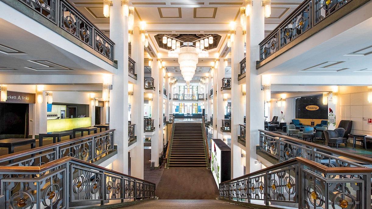 Elegante Lobby des Friedrichstadt-Palastes mit breiter Treppe, Kronleuchtern und verzierten Geländern.