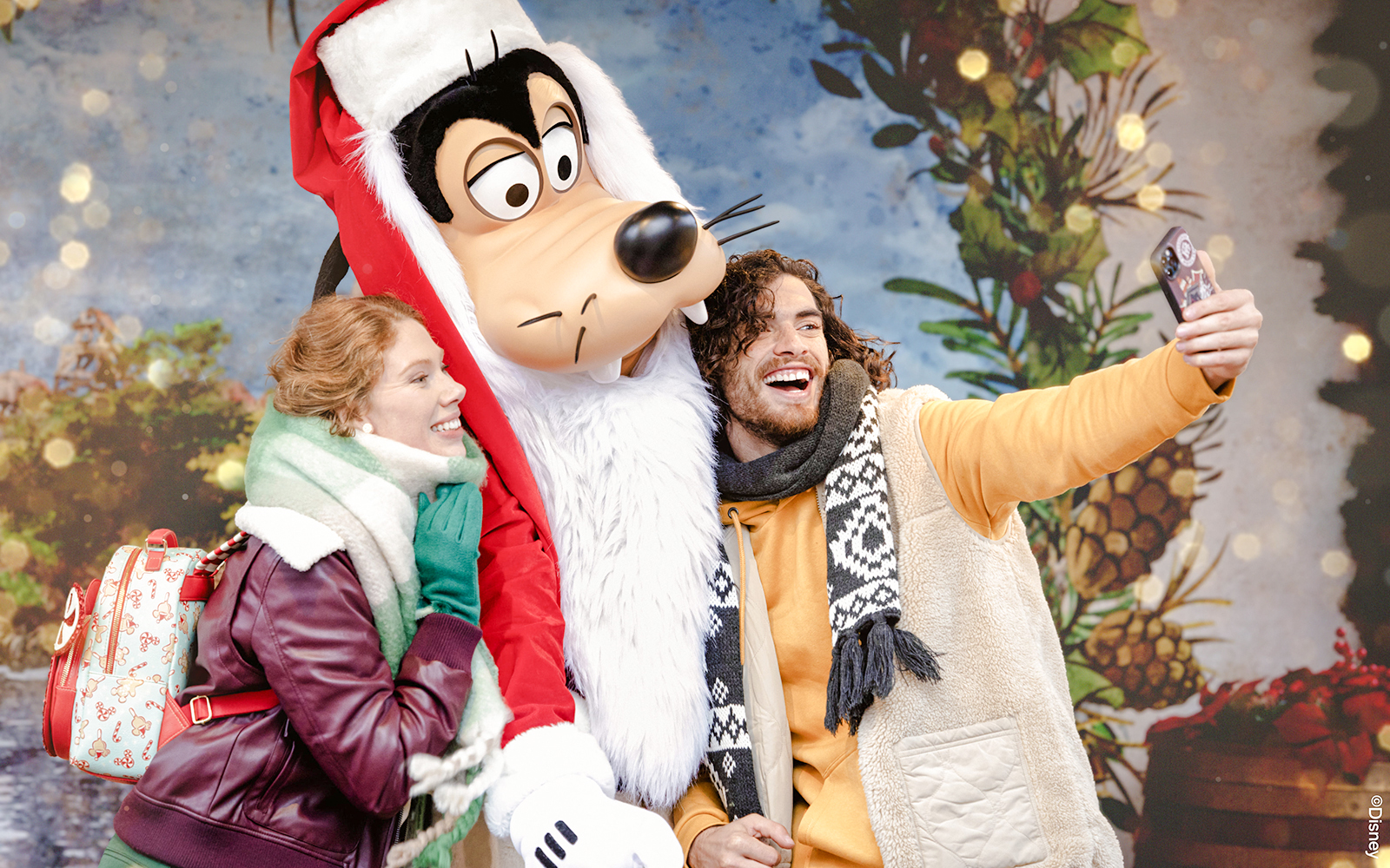 Tourists taking a selfie with Goofy during Disneyland Christmas 2025 celebrations.