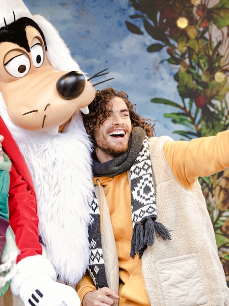 Tourists taking a selfie with Goofy during Disneyland Christmas 2025 celebrations.