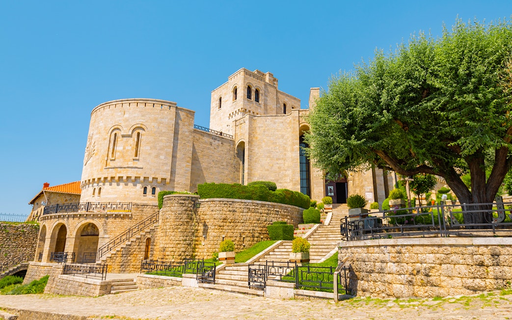 Kruja Castle in Albania with stone walls and lush greenery.