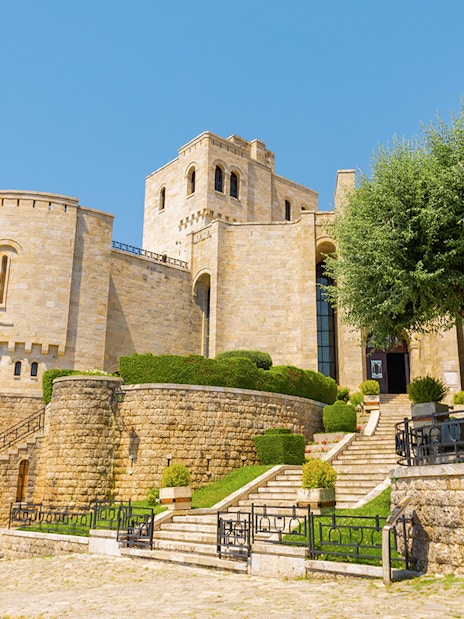 Kruja Castle in Albania with stone walls and lush greenery.