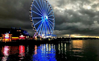 Seattle Great Wheel illuminated at night on the waterfront, part of the Harbor of Secrets game.