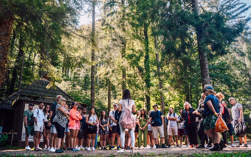 Tour group listening to a guide in Plitvice Lakes National Park forest.
