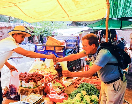 Tourists purchasing vegetables at a market stall in Ourika Valley, Morocco.