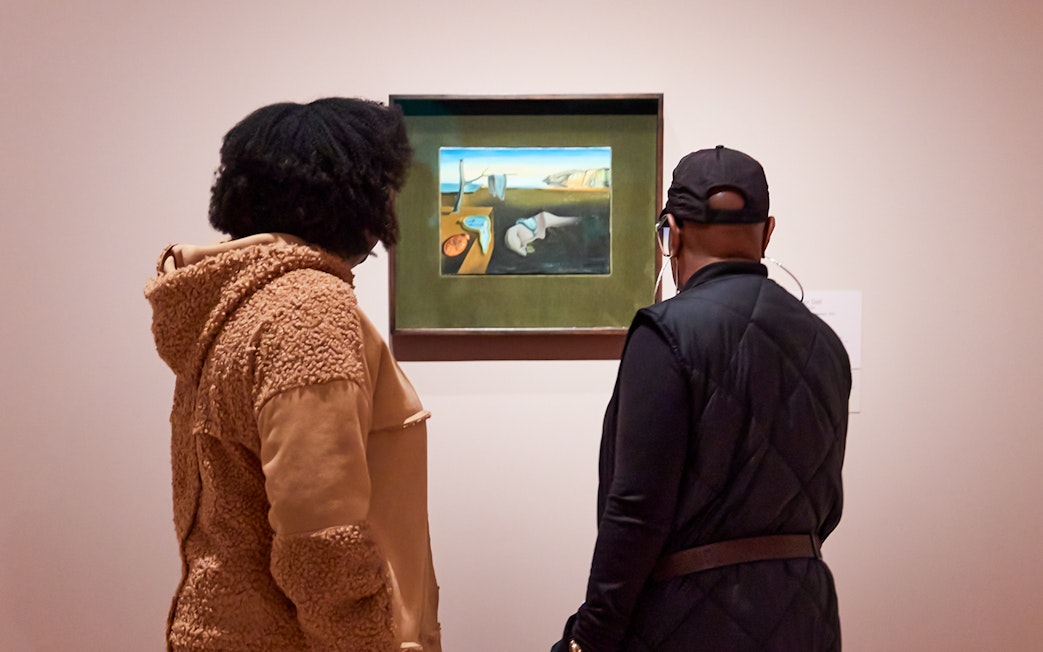 Visitors viewing a Salvador Dalí painting at a museum exhibition.