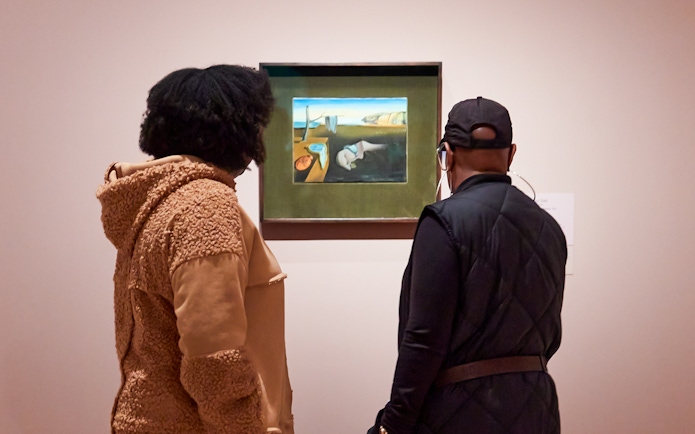 Visitors viewing a Salvador Dalí painting at a museum exhibition.