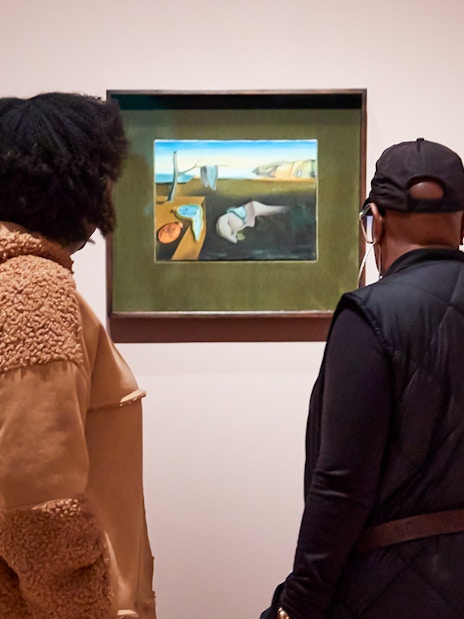 Visitors viewing a Salvador Dalí painting at a museum exhibition.