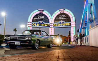 Classic cars under neon Old Town sign in Orlando at dusk.