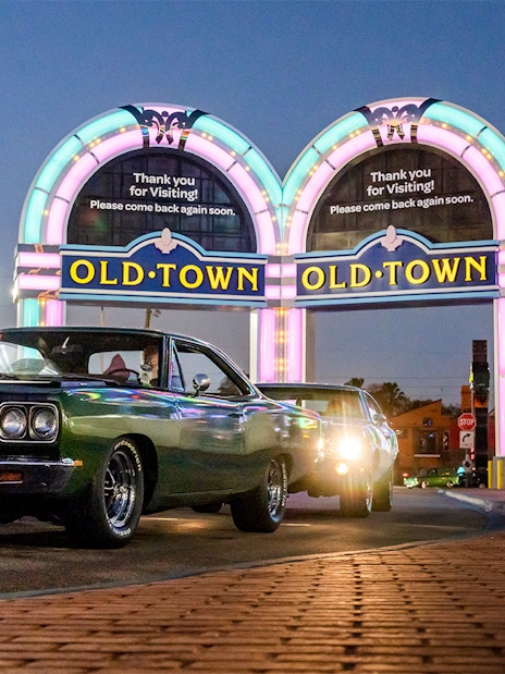 Classic cars under neon Old Town sign in Orlando at dusk.