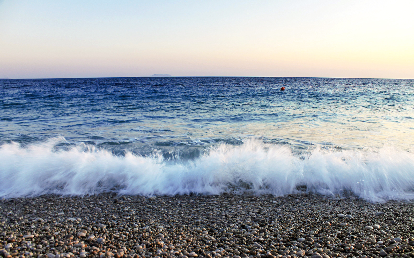 Waves crashing on a pebble beach at sunset near Vlore, Albania.