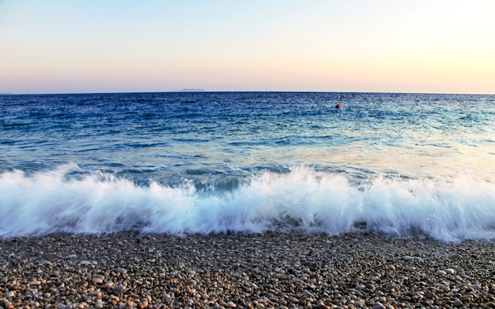 Waves crashing on a pebble beach at sunset near Vlore, Albania.