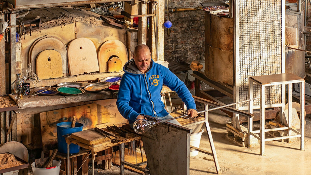 Artisan crafting glass at Murano workshop, demonstrating traditional glass blowing techniques in Venice, Italy.