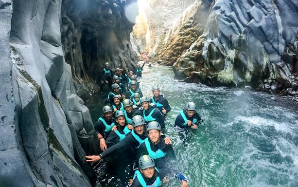 Group canyoning in Alcantara Gorge, Sicily, wearing helmets and wetsuits.