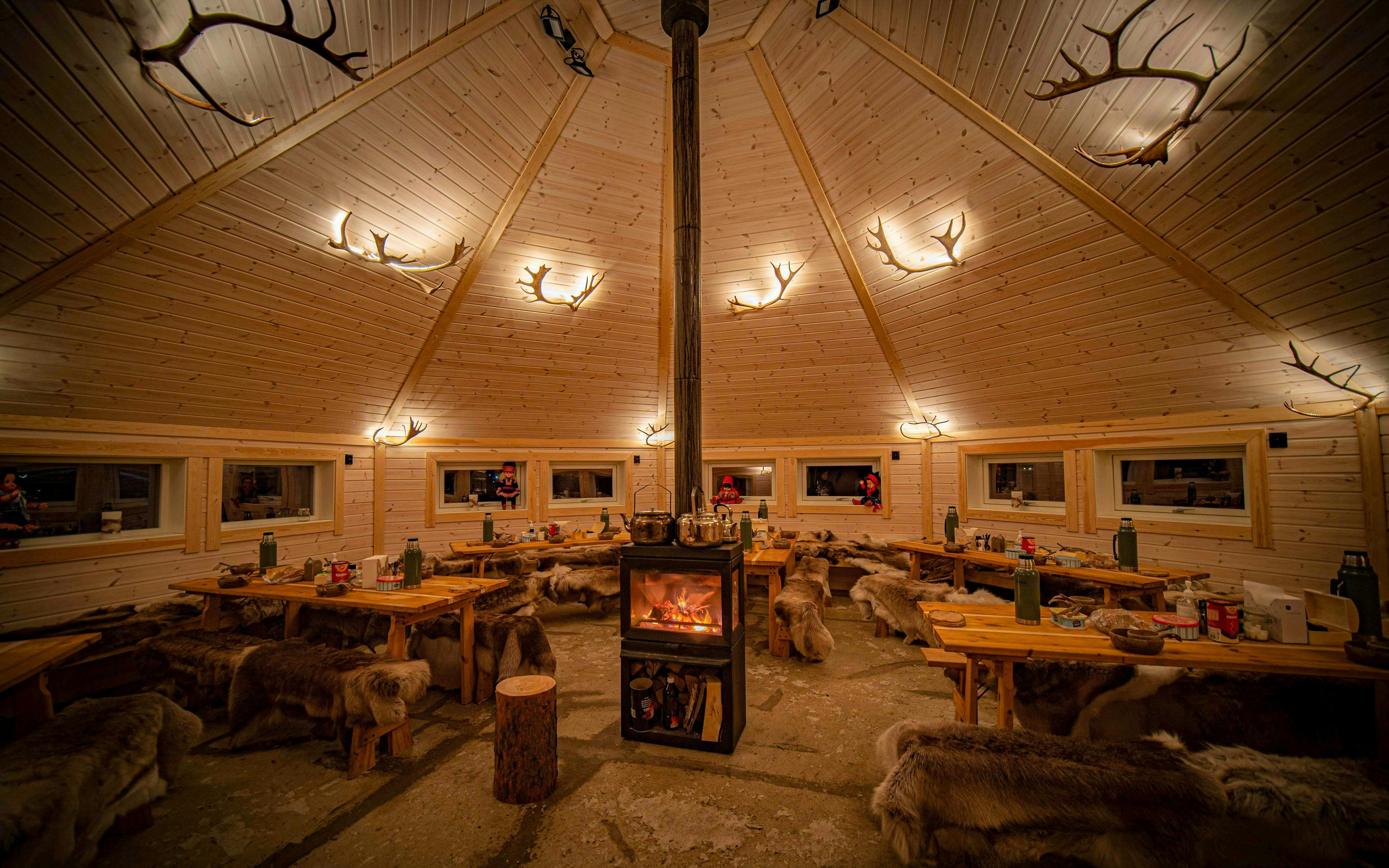 Wooden hut interior with central fireplace and reindeer hides, Tromso.