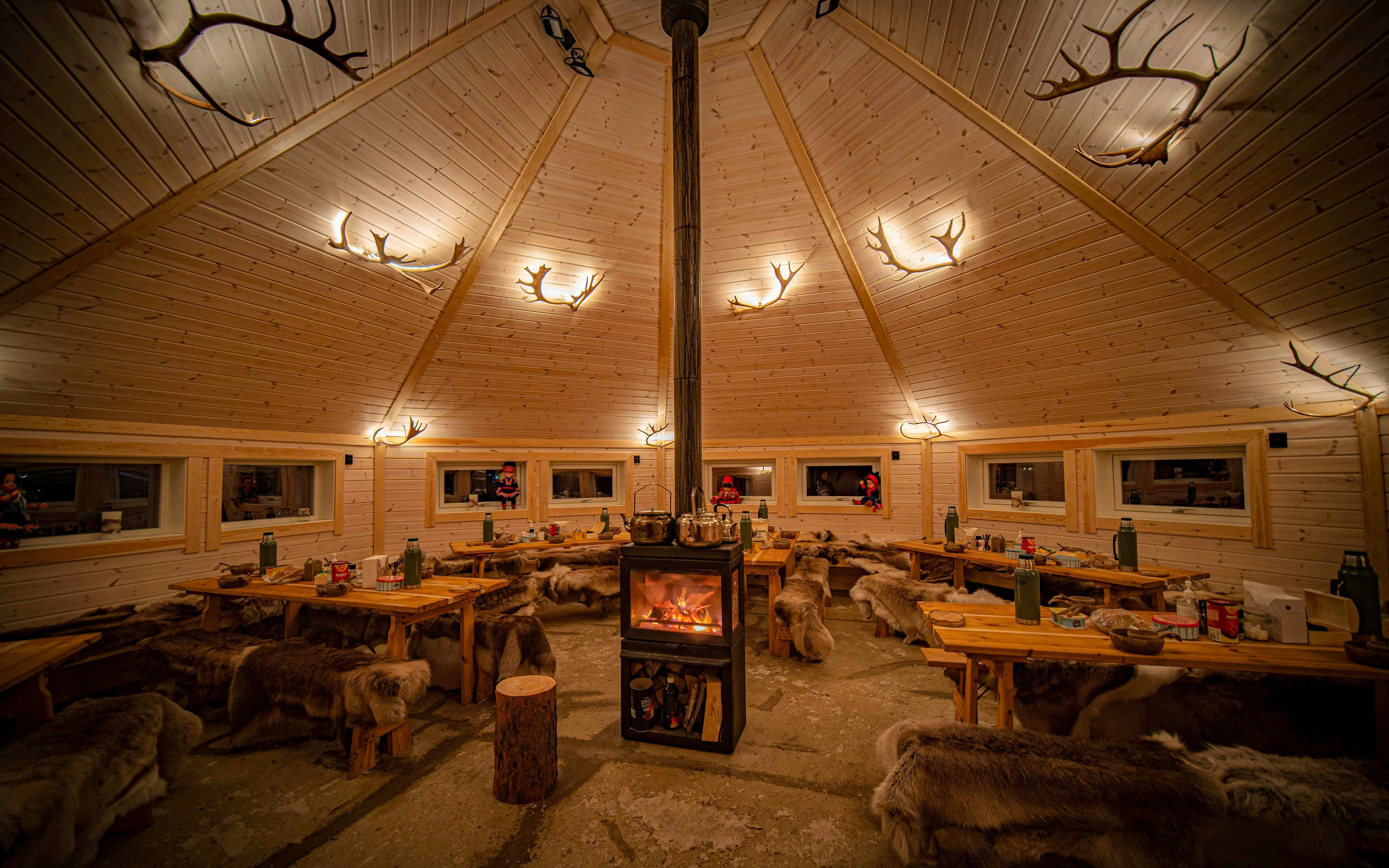 Wooden hut interior with central fireplace and reindeer hides, Tromso.