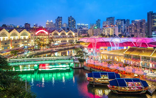 Clarke Quay waterfront with colorful lights and boats in Singapore city tour.