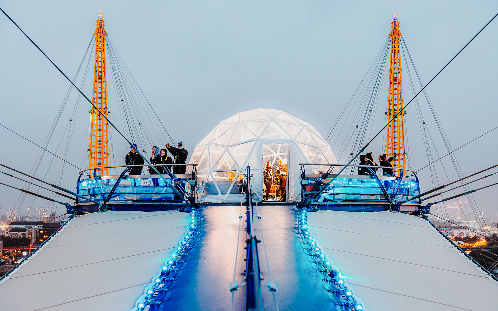 Visitors at the O2 Arena's snow globe experience, London, with illuminated walkway.
