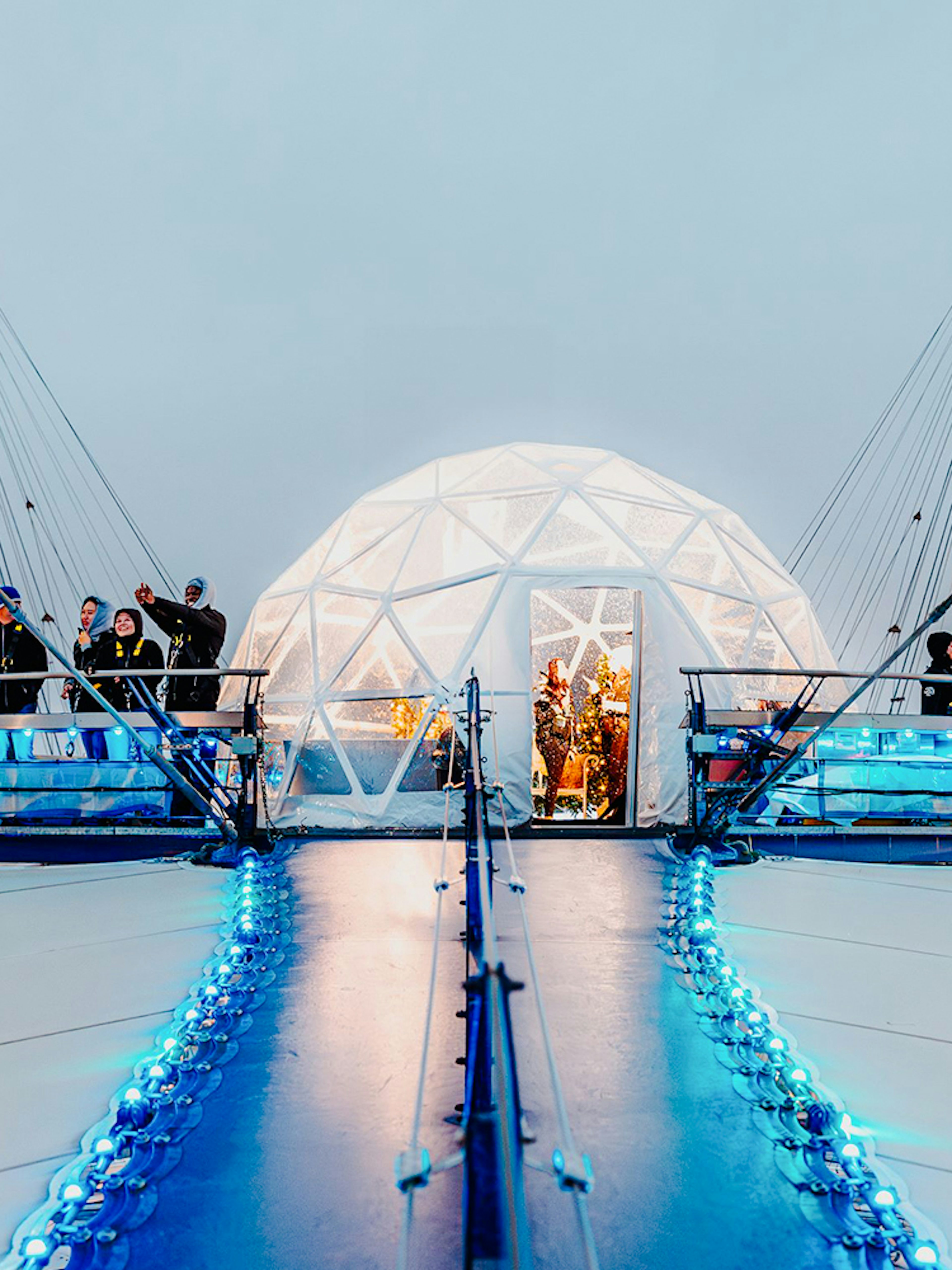 Visitors at the O2 Arena's snow globe experience, London, with illuminated walkway.