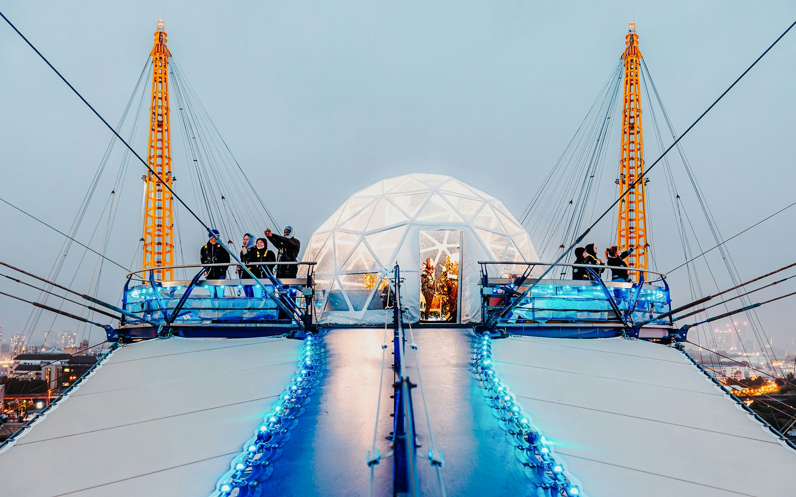 Visitors at the O2 Arena's snow globe experience, London, with illuminated walkway.