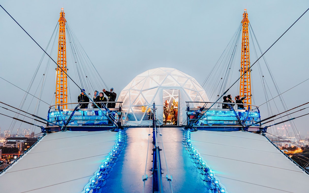 Visitors at the O2 Arena's snow globe experience, London, with illuminated walkway.