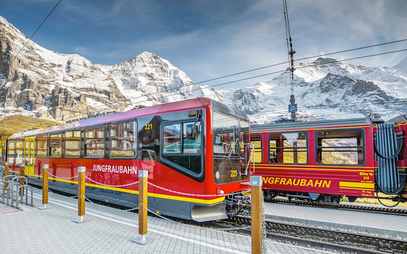 Jungfraubahn train at station with snow-covered mountains in Berner Oberland, Switzerland.