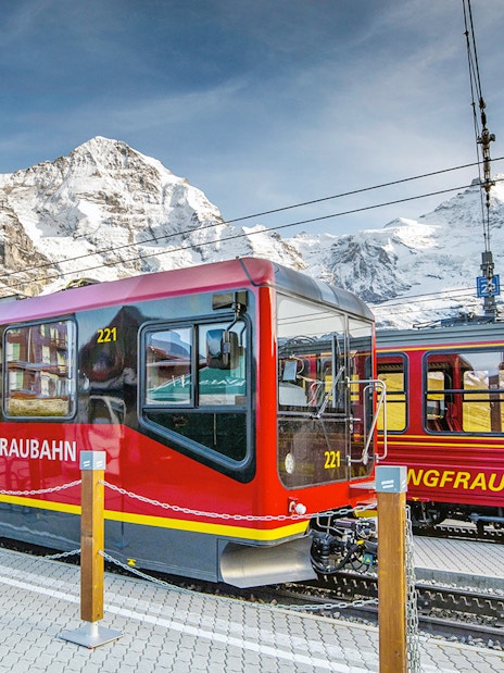 Jungfraubahn train at station with snow-covered mountains in Berner Oberland, Switzerland.