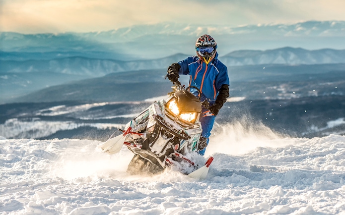 Snowmobile rider on snowy terrain with mountain backdrop in Zakopane.