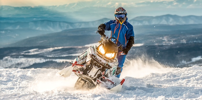 Snowmobile rider on snowy terrain with mountain backdrop in Zakopane.