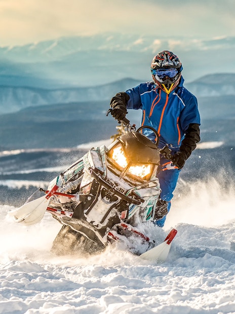 Snowmobile rider on snowy terrain with mountain backdrop in Zakopane.