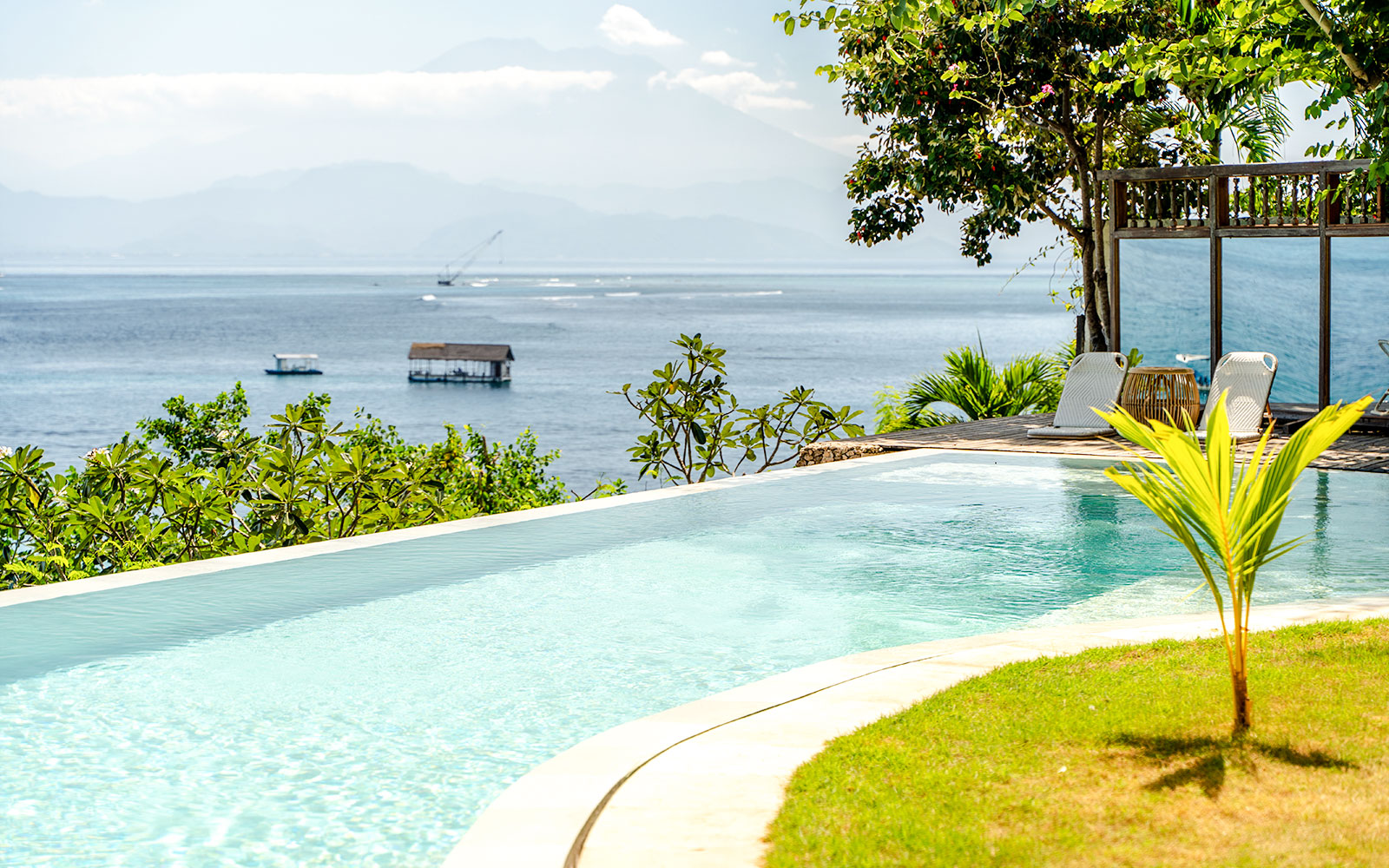 Infinity pool overlooking ocean view in Nusa Penida, with lounge chairs and tropical greenery.