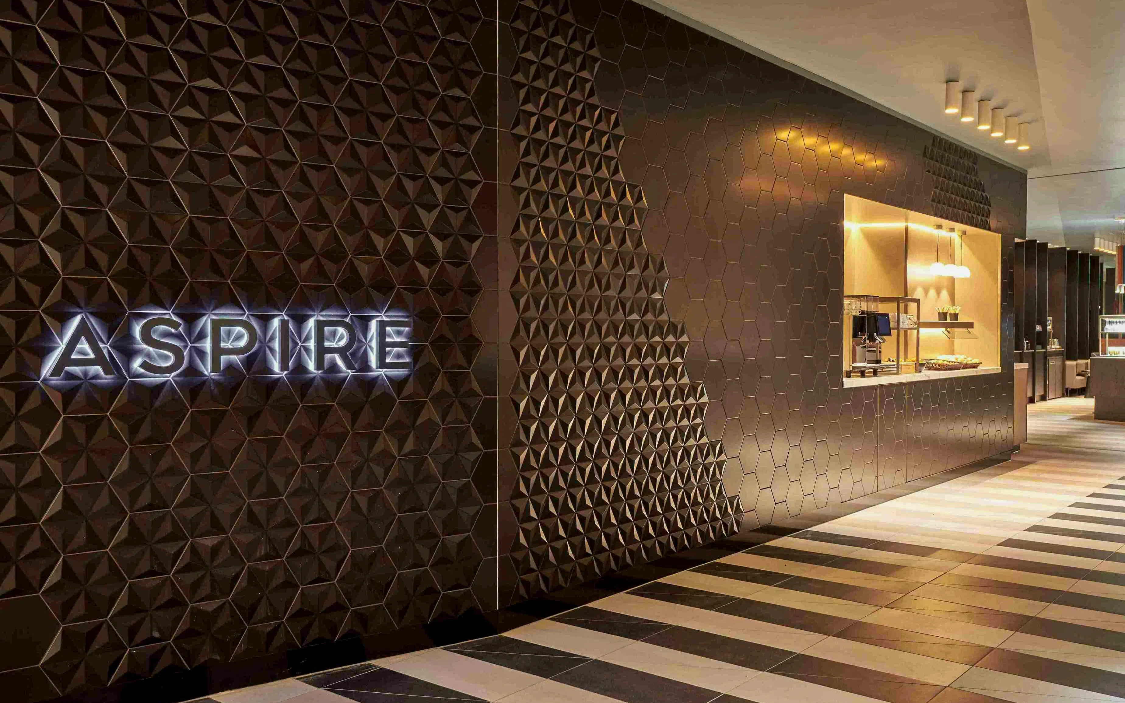 Aspire Lounge entrance with geometric wall design at Schiphol Airport Terminal 2.