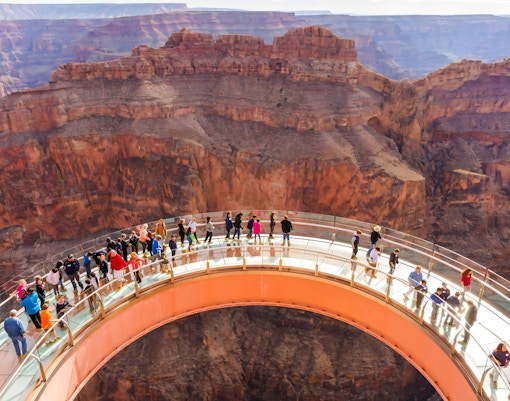 Visitors walking on the Grand Canyon Skywalk with canyon views in the background.