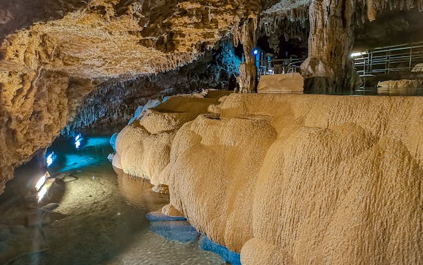 Underground limestone cave at Okinawa World with illuminated stalactites and stalagmites.