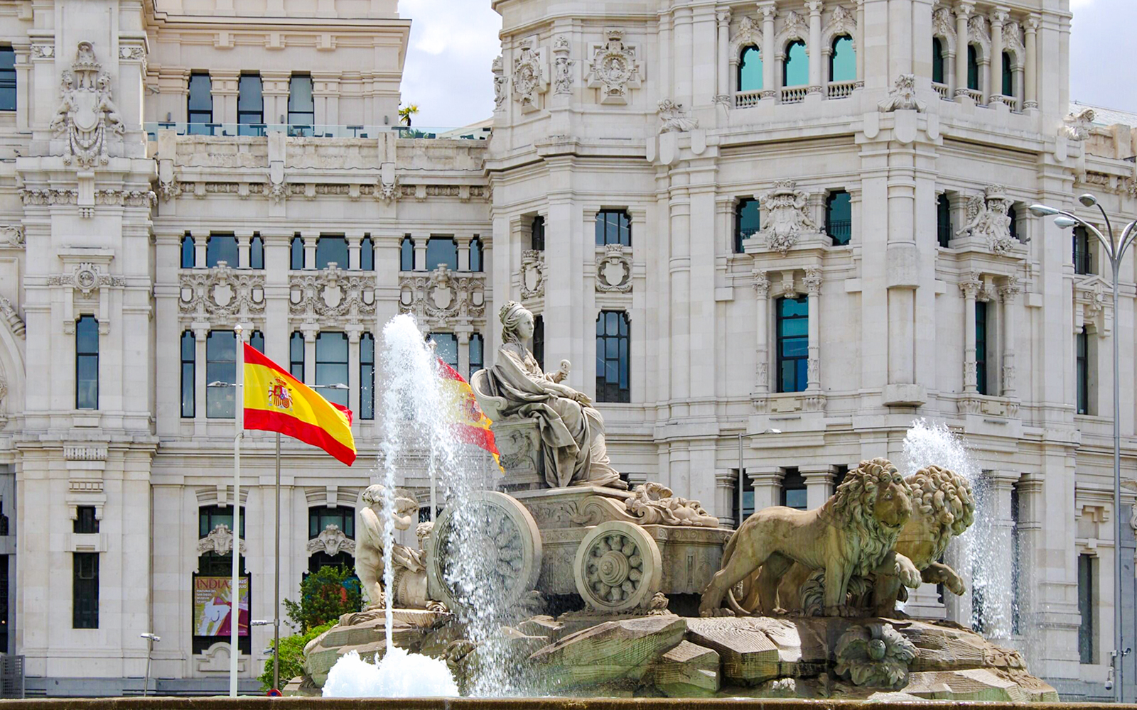 Cibeles Fountain with Spanish flags in front of Palacio de Cibeles, Madrid, Spain.