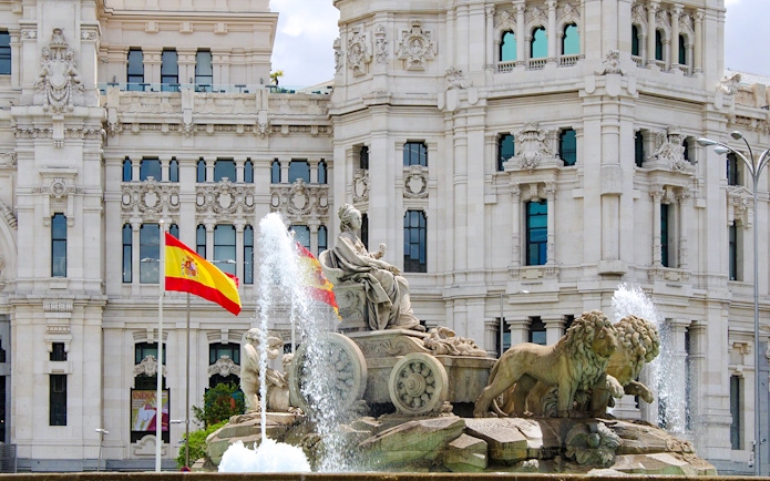Cibeles Fountain with Spanish flags in front of Palacio de Cibeles, Madrid, Spain.