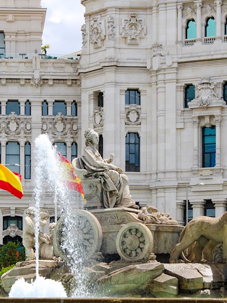 Cibeles Fountain with Spanish flags in front of Palacio de Cibeles, Madrid, Spain.